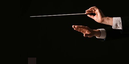 Hände eines Dirigenten mit Taktstock beim Dirigieren