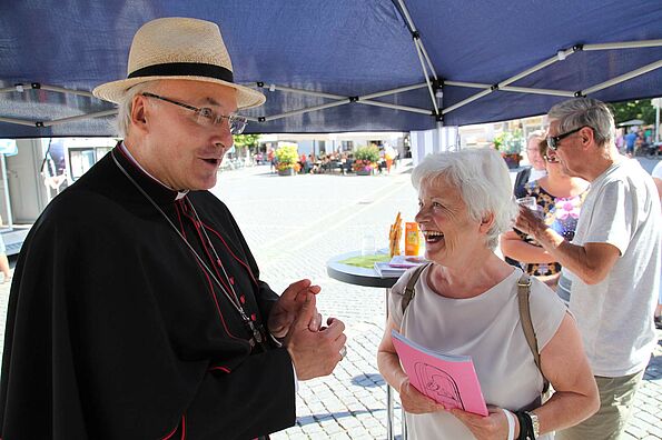 Bischof und ältere lachende Frau im Gespräch