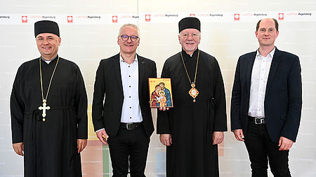 Ukrainischer Bischof und Bischofsvikar neben zwei Männern von der Caritas